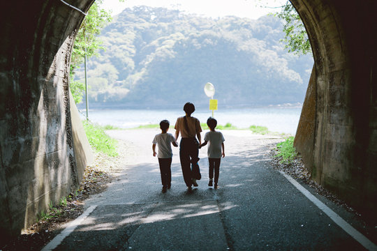 Rear view of woman with her children walking on road
