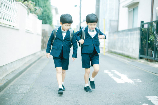 Siblings in uniform walking on road