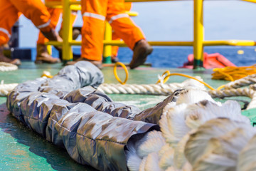 Fototapeta na wymiar Offshore worker preparinf hawser rope for anchor mooring to platform jacke leg