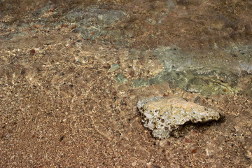 Summer background of hot sand with sea or ocean wave bubbles with copy space for card or advertisement at dawn or sunset