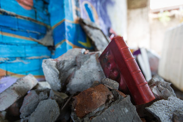 Libro rosso tra macerie di palazzo con graffiti