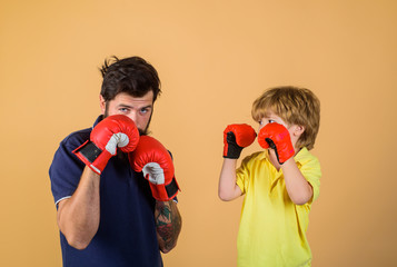 Father is training his son boxing. Little boy in boxing gloves working out with coach at gym....