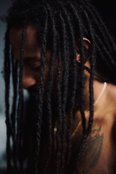 Portrait of man with tattoo on chest displaying dreadlocks