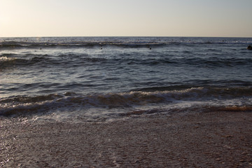 Summer background of hot sand with sea or ocean wave bubbles with copy space for card or advertisement at dawn or sunset