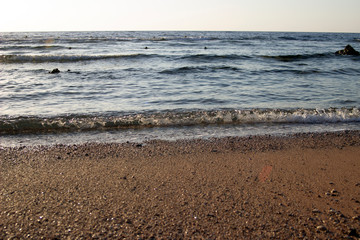 Summer background of hot sand with sea or ocean wave bubbles with copy space for card or advertisement at dawn or sunset