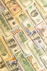 Banknotes of one hundred dollars and another denomination, lie in neat rows as a background. Business concept, currency exchange.