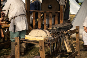 Reconstruction of the forge. Old crafts. Craftsmen rest from work. Blacksmith Furs. Metal tools. Blacksmith forge. Medieval historical role-playing games. Dressed in an old outfit. Bugle.