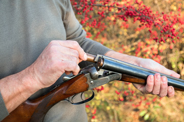 The man hunter charging the double-barreled shotgun with cartridges. 16 gauge
