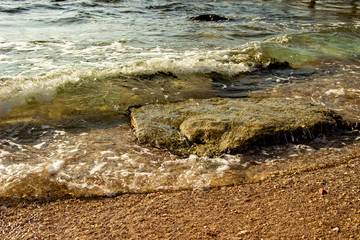 Summer background of hot sand with sea or ocean wave bubbles with copy space for card or advertisement at dawn or sunset