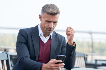 Mobile is lifestyle not technology. Mature businessman use mobile device in cafe. Handsome man hold...
