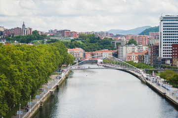 Fototapeta na wymiar Bilbao, Spain - August 15 2019: View of the buildings in Bilbao by the river, on a cloudy day, beautiful destination in Basque county