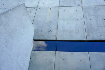Cement wall and a glass reflected cloud in the sky