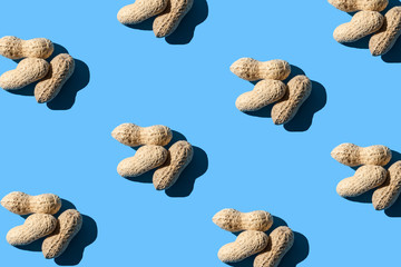 Fototapeta na wymiar Pattern of three peanuts on a light blue background. Flat lay. Minimal background texture of food nut. Creative layout