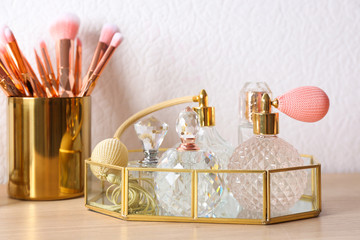 Luxury perfumes and makeup brushes on wooden dressing table
