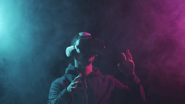 Portrait of a man in virtual reality helmet. Obscured dark face in VR goggles. Internet, darknet, gaming and cyber simulation.