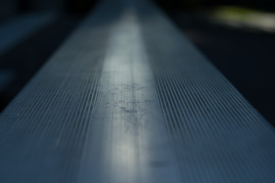 Straight Path On Metal Bench With Faint Sun Reflection