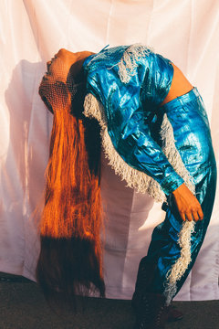 Side view of model in metallic blue outfit bending backwards