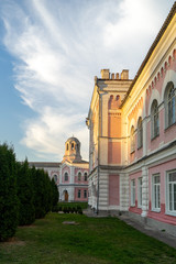 The old manor is a museum on a background of blue sky with beautiful clouds. Green lawn and well-groomed shrubs.