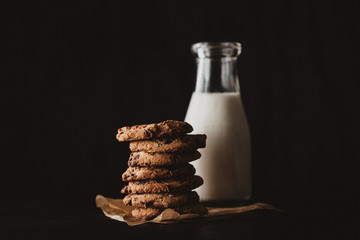 Choco chip cookies on unbleached parchment paper with bottle of milk