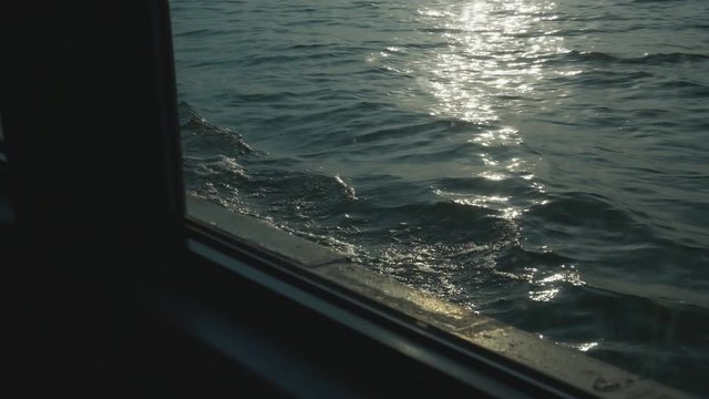 View of the sun flare through the ship's porthole in the open sea