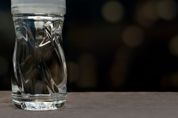 Close-up clear a plastic bottle of water isolated on the table and black bokeh background.