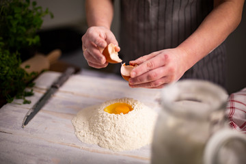 Obraz na płótnie Canvas Traditional home cooking. A woman sticks an egg into flour, prepares homemade pasta dough
