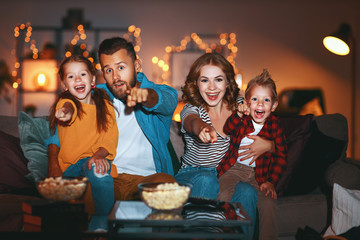 family mother father and children watching projector, TV, movies with popcorn in   evening   at...