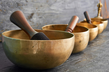 Tibetan singing bowls with sticks on the dark background - music instruments for meditation, relaxation after yoga practice and healing massage
