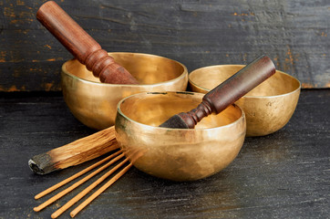 Tibetan singing bowls with palo santo and aroma sticks on the dark background.  Nepal music instruments for meditation, relaxation after yoga practice and healing massage