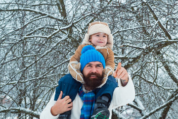 Father giving son ride on back in park. Child sits on the shoulders of his father. Portrait of...