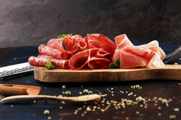 Food tray with delicious salami, coppa, crudo and herbs. Meat platter with selection on rustic table