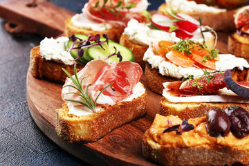 Assorted bruschetta with various toppings. Appetizing bruschetta or brie crostini. Variety of small sandwiches. Mix bruschetta on table