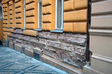 wall of an old house with crumbling stucco under the windows