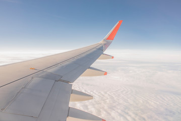 Wing of the plane outside of the window. Airplane above the sky. Airplane above the cloud. Looking...