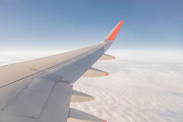 Muurstickers Vleugel van het vliegtuig buiten het raam. Vliegtuig boven de hemel. Vliegtuig boven de wolk. Buiten het vliegtuigraam kijken. © Colin