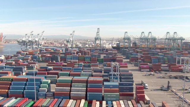 PORT OF LOS ANGELES, CALIFORNIA, UNITED STATES OF AMERICA, MARCH 2019: AERIAL: Flying over the massive freight dockyard in Los Angeles on a sunny day. Large freight containers are processed at a port.