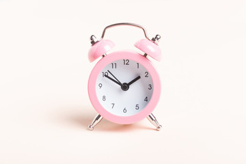 Little pink alarm clock on a pink background