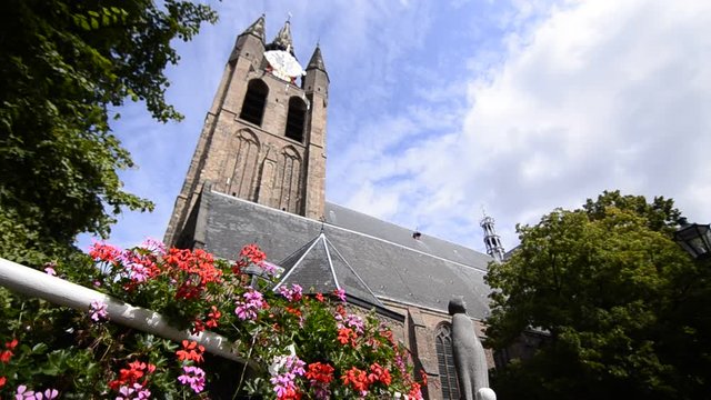 Delft, Holland, August 2019. The bell tower of the old church, the Oude Kerk, stands out imposingly over the city. Planters give color to the image. Change of focus.