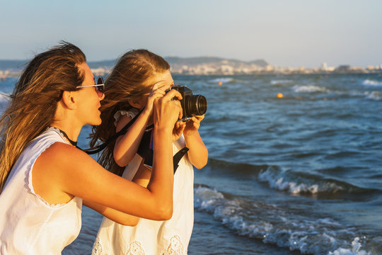 Little photographer - mom and daughter take pictures of landscapes near the sea