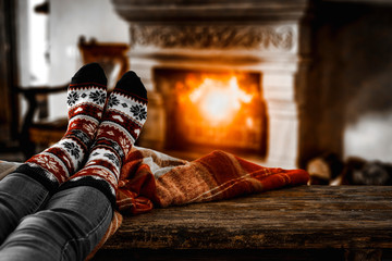 Woman legs with christmas socks and fireplace background in home interior 