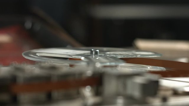 Running tape on reel in old vintage professional sound recorder close up