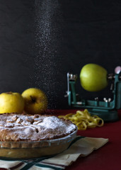 Apple pie with sugar rain. Black background with apples. Food concept