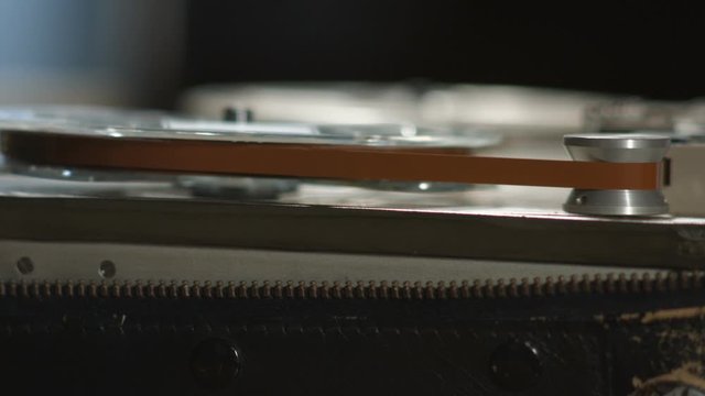 Running tape on reel in old vintage sound recorder start and stop close up