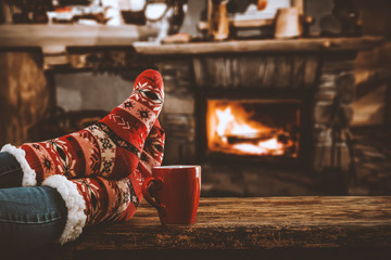 Woman legs with christmas socks and fireplace background in home interior 