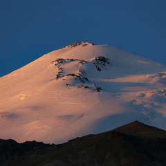 Dawn over the eastern peak of Mount Elbrus. The snow-covered peaks of a stratovolcano are lit by...