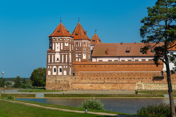 View of the Belarusian Mir castle complex made of red brick against a bright blue sky on a sunny cloudless day