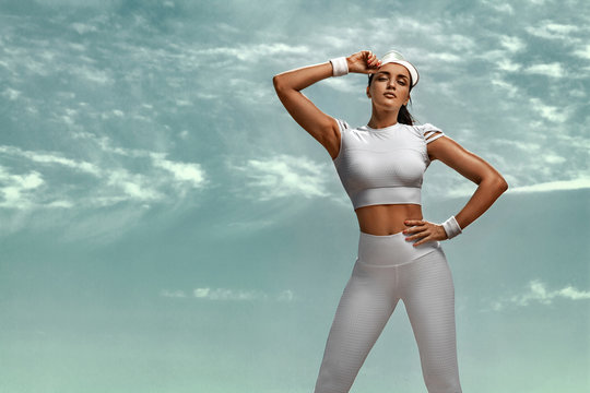 Sporty and fit young woman athlete relaxed after training at the desert. Cloudy day on coast. The concept of a healthy lifestyle and sport. Woman in white sportswear.