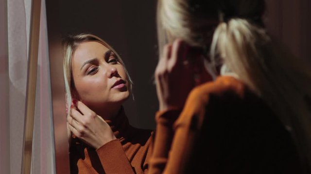 Reflection on mirror, young woman putting earrings getting ready,static
