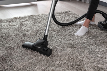 Home cleaning concept - woman cleaning the room with carpet sweeper in close-up