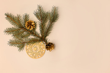 Christmas composition. Spruce branch, Golden cones and ornaments on a light beige background.